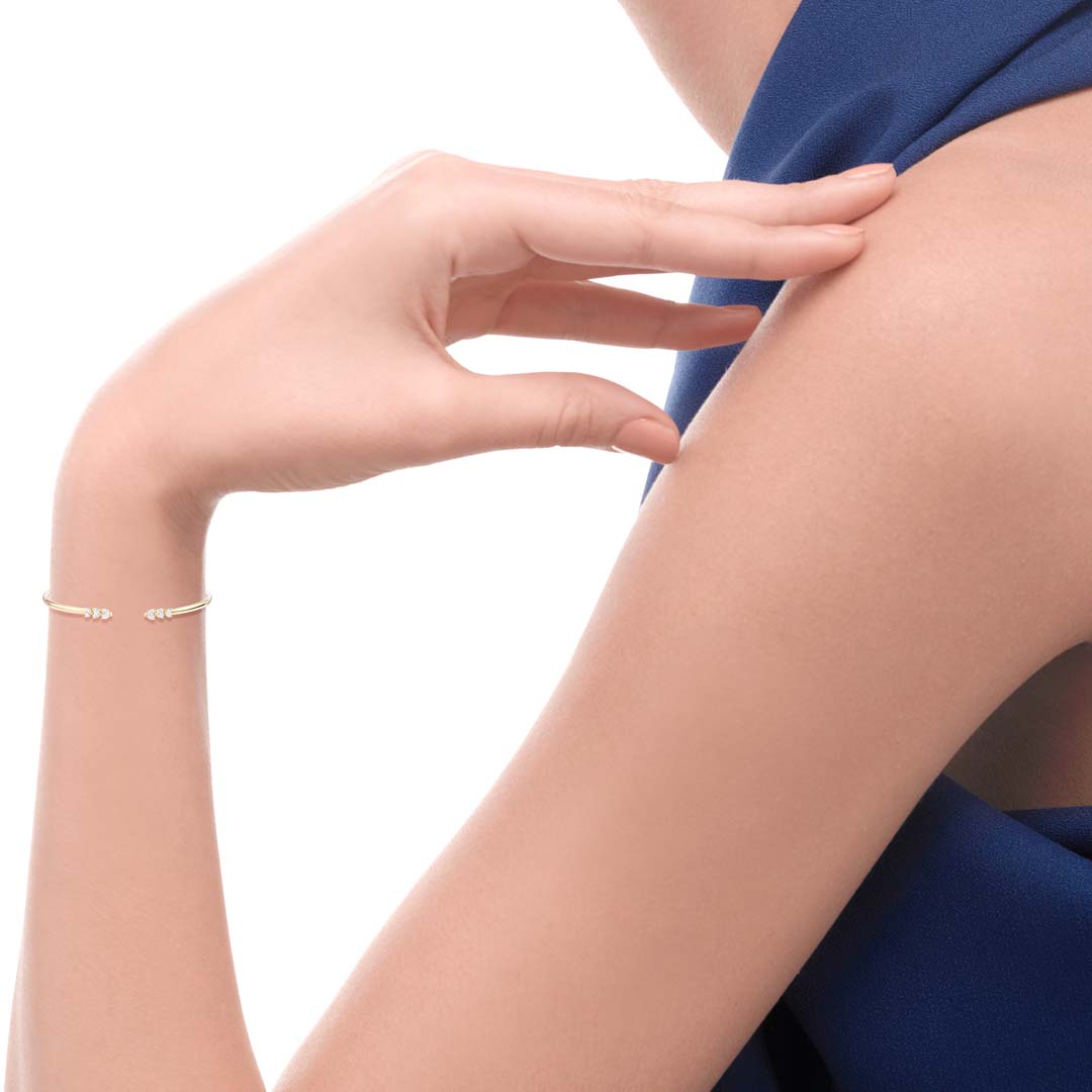 Close-up of a person's arm with a gold bracelet on a white background
