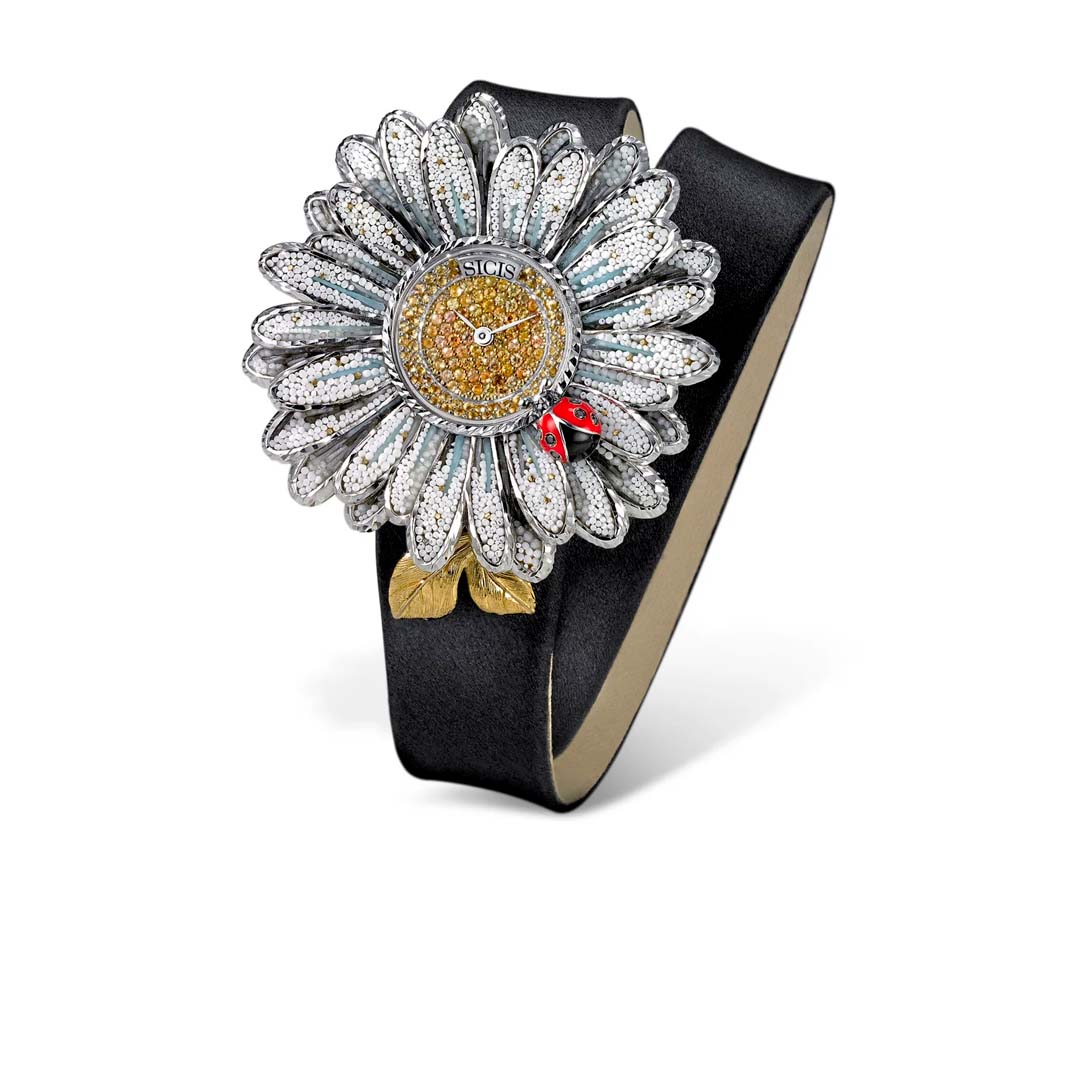 A poetic expression of Italian artistry, the White Daisy Watch by Sicis Jewels captures the delicate balance between time and beauty. Crafted in 18k white gold, its dial blooms with a meticulously hand-set micromosaic, a signature Sicis technique that transforms thousands of miniature tesserae into a luminous daisy motif, petal by petal.

Encircling this miniature work of art, a halo of&nbsp;black diamonds and yellow sapphires adds contrast and brilliance, echoing the natural harmony of night and sunlight.