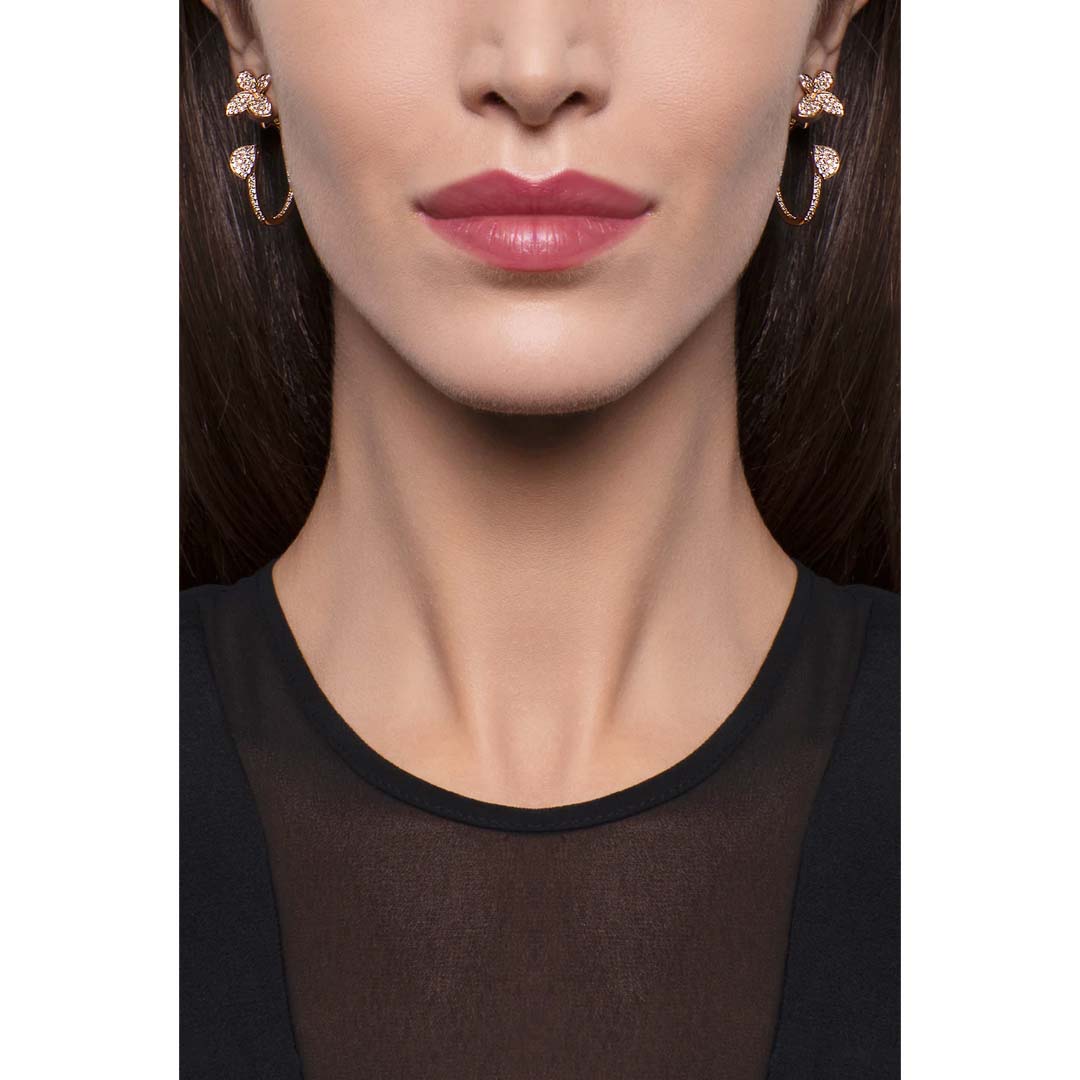 Close-up of a woman's face wearing gold earrings with a white background