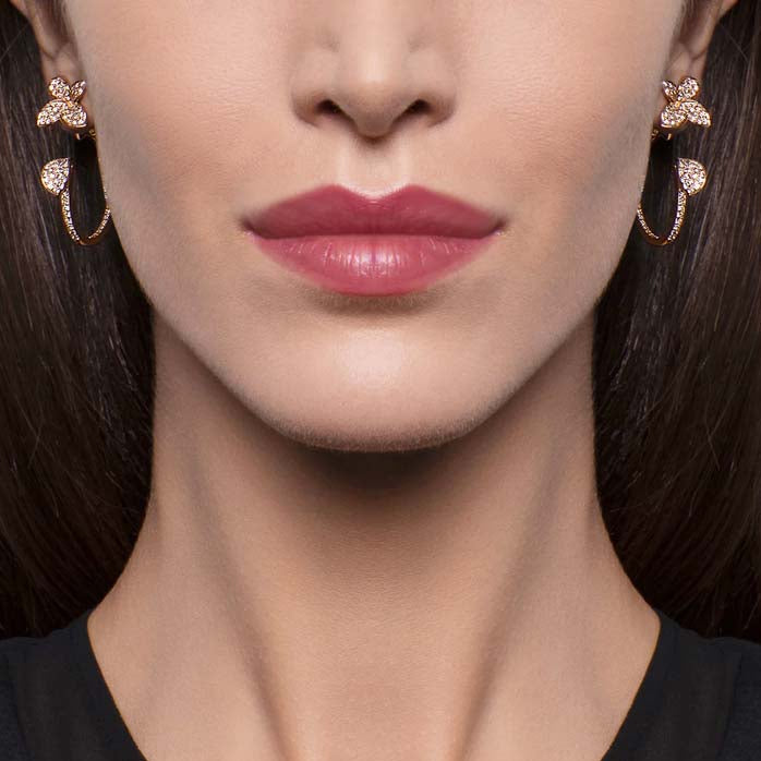 Close-up of a woman's face wearing gold earrings with a white background